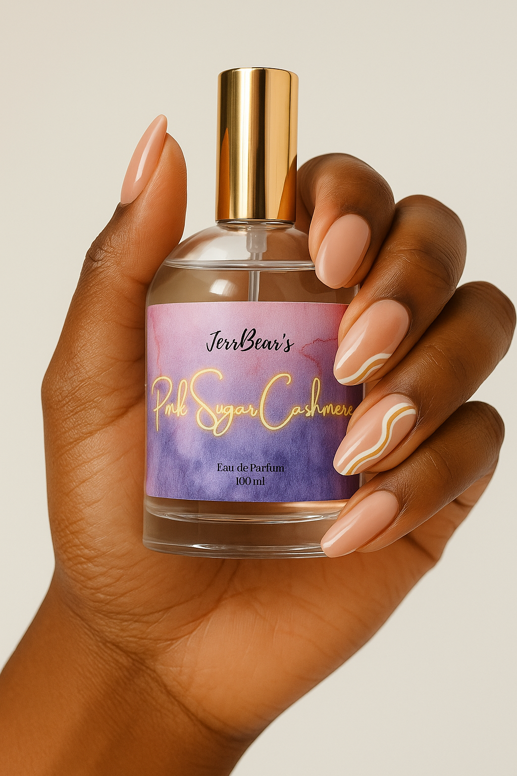 Hand holding a perfume bottle labeled 'Tori Bear's Pink Sugar Cashmere' against a neutral background